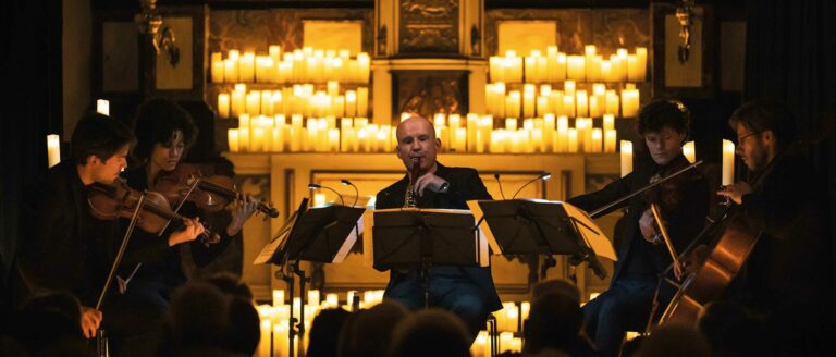 Het roalsnd hendrikx ensemble met op de achtergrond een zee van kaarsen.
