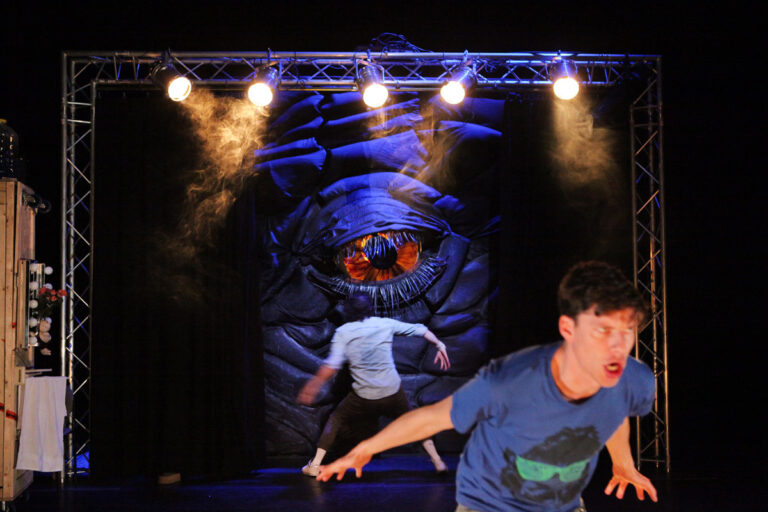 Groot oog op de achtergrond met twee acteurs die wegrennen