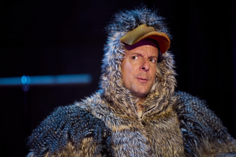 Een persoon in een kostuum dat lijkt op een vogel met een opvallende grauwe vacht en een gele snavel.