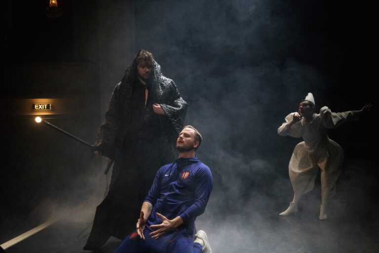 Jim Bakkum op zijn knieën met twee andere acteurs om hem heen