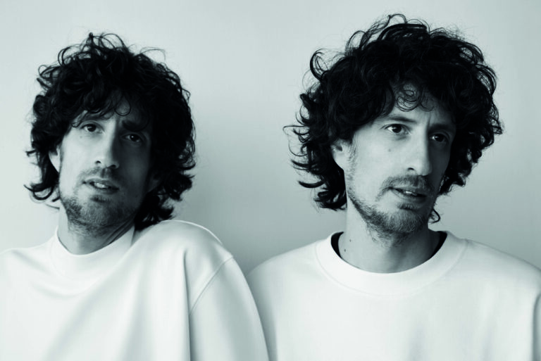 Een zwartwit foto van een tweeling met allebei een witte trui aan.