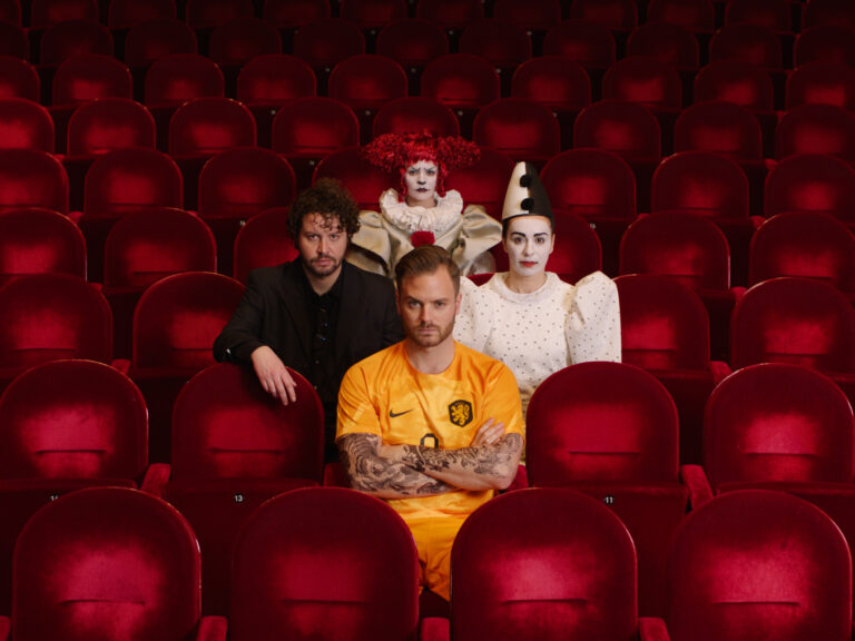 4 acteurs zitten op rode theaterstoelen