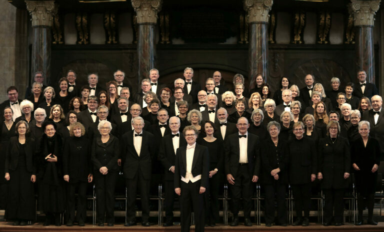 Het koor want in een grote groep, netjes gekleed, lachend de camera in kijkt.
