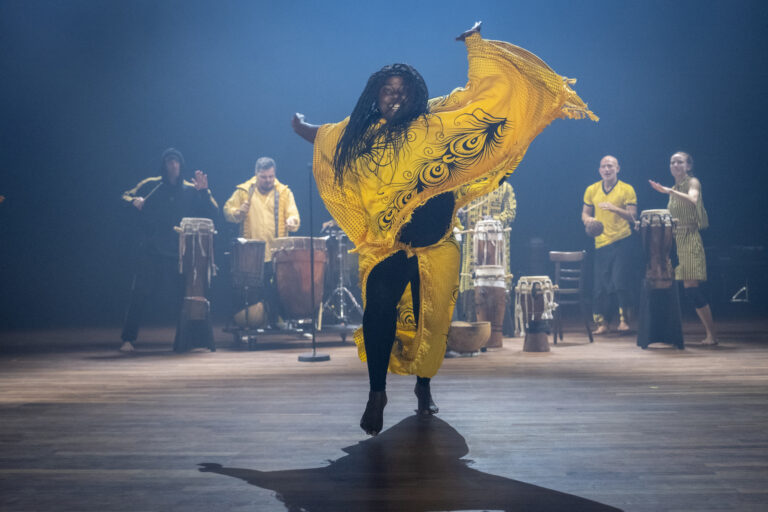 Danseres in gele kleding met armen wijd