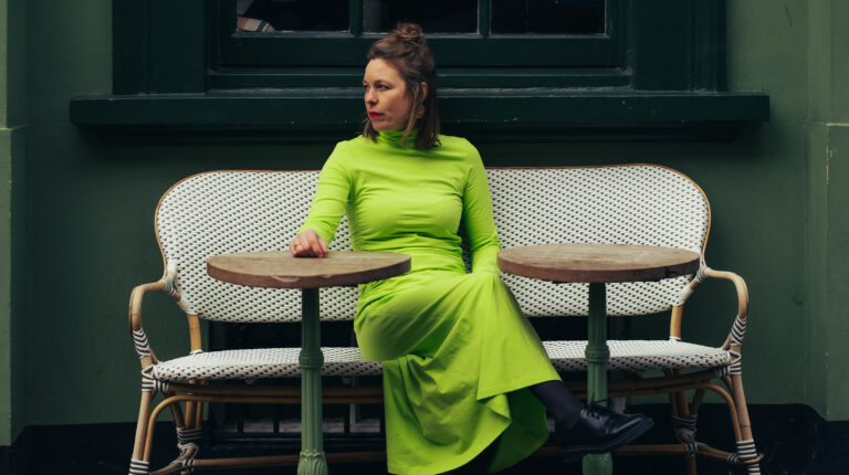 Tineke Postma in een felle limoengroene jurk op een terras
