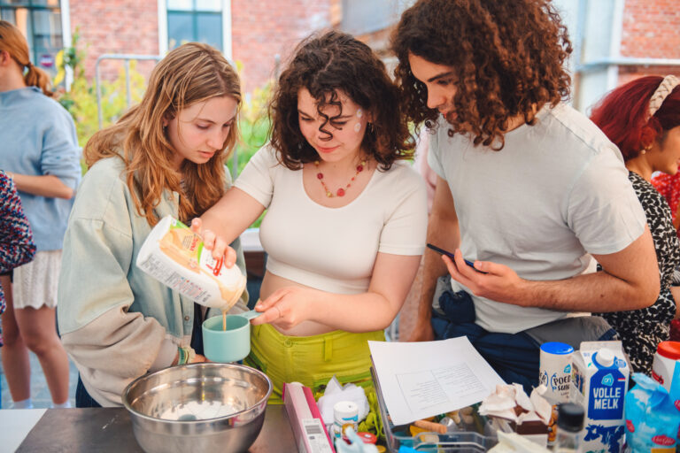 Drie mensen zijn samen in een keuken bezig met het bereiden van voedsel.