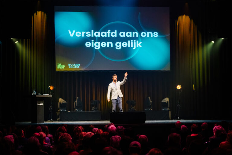 Lammert Kamphuis op het podium bij zijn theatercollege Verslaafd aan ons eigen gelijk