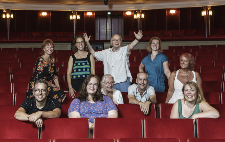 Groep Wijkspotters in de de Schouwburg zaal op de rode stoelen.