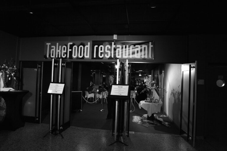 Een zwart-witfoto van de ingang van een restaurant met de naam 