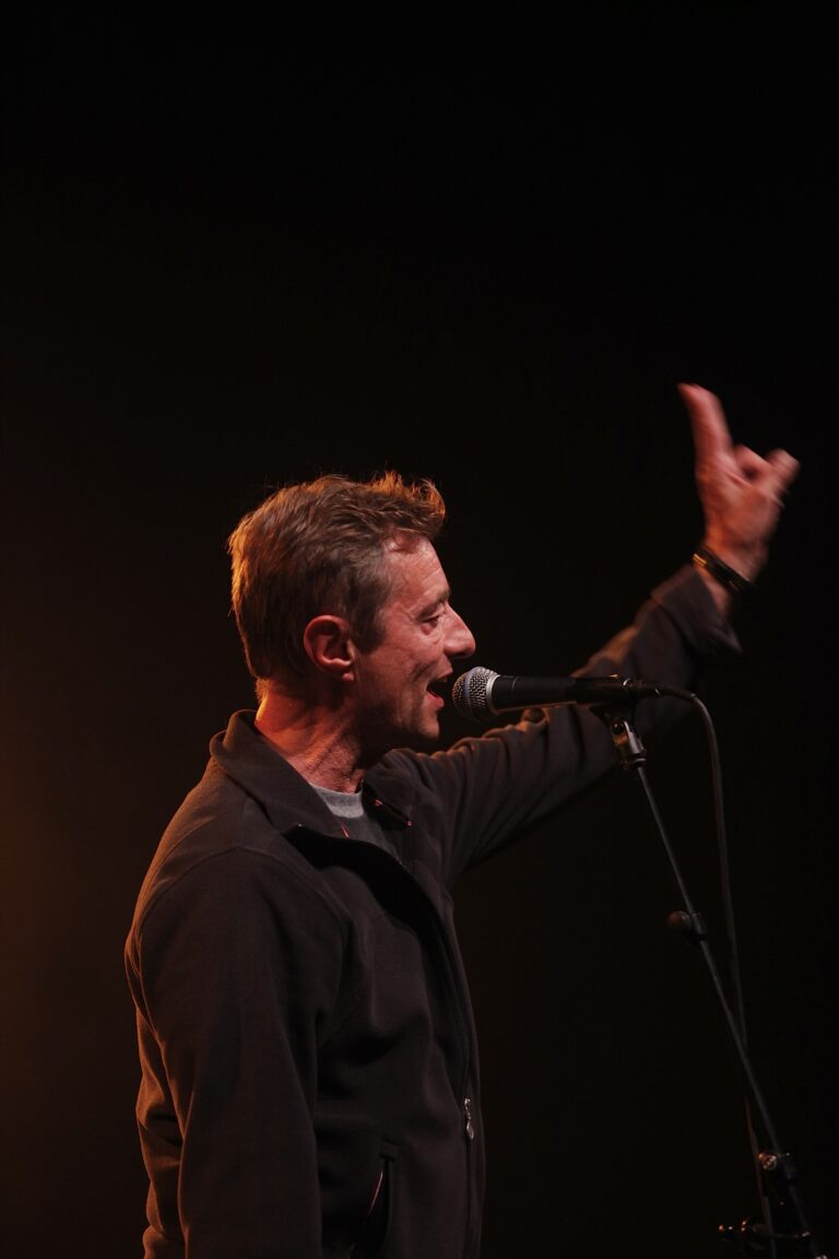 Een muzikant zingt in een microfoon terwijl hij zijn hand opsteekt.