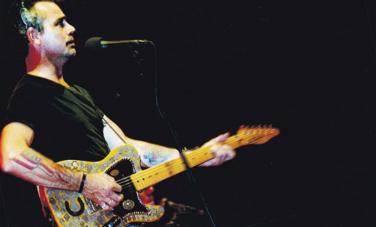 Een muzikant speelt gitaar tijdens een optreden op het podium.