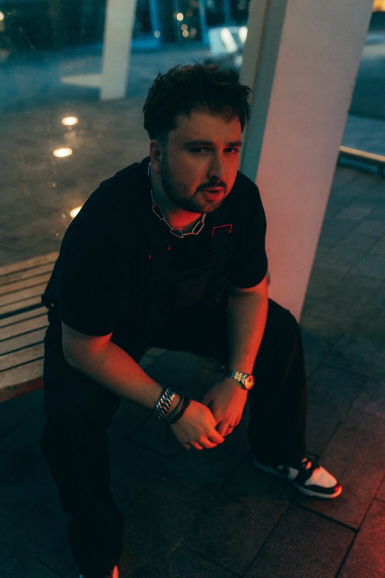 Jongen in zwarte kleding zit op een bankje