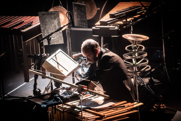 Een muzikant bespeelt verschillende instrumenten op een groot podium.