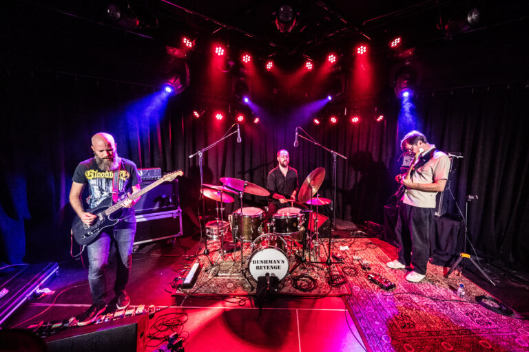 Een band speelt live op een podium met kleurrijke verlichting.