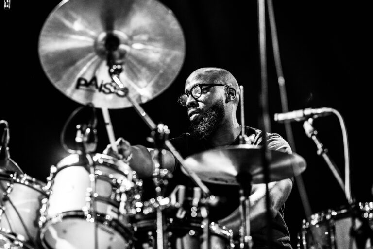 Een drummer bespeelt zijn drumstel tijdens een optreden op het podium.