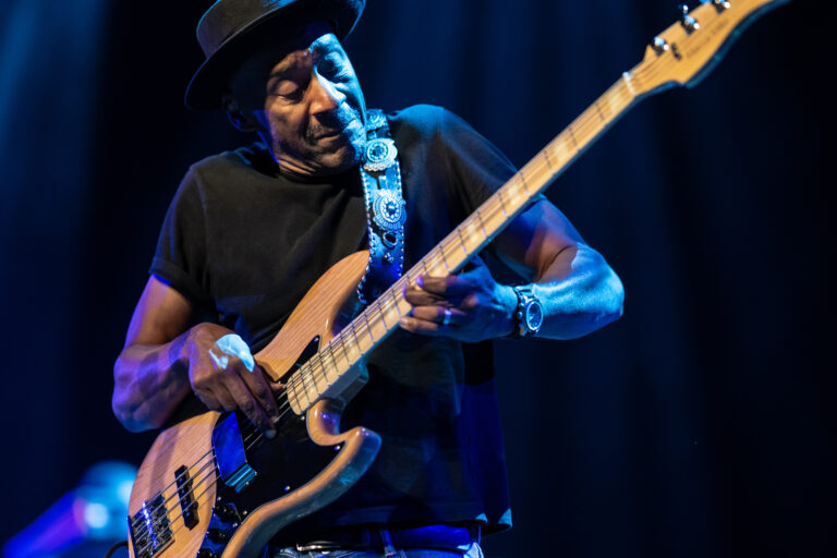 Een muzikant speelt op een elektrische basgitaar tijdens een live optreden.