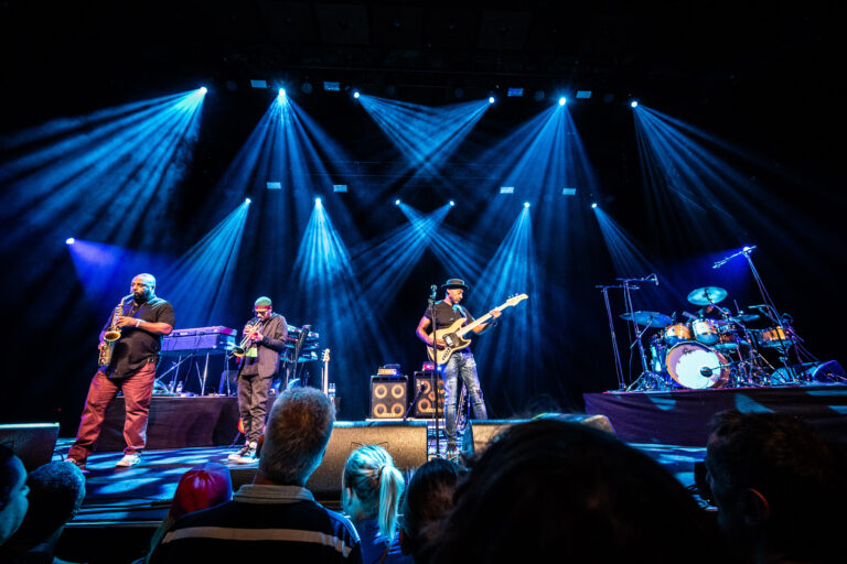 Een live band speelt op een podium met spectaculaire blue verlichting.