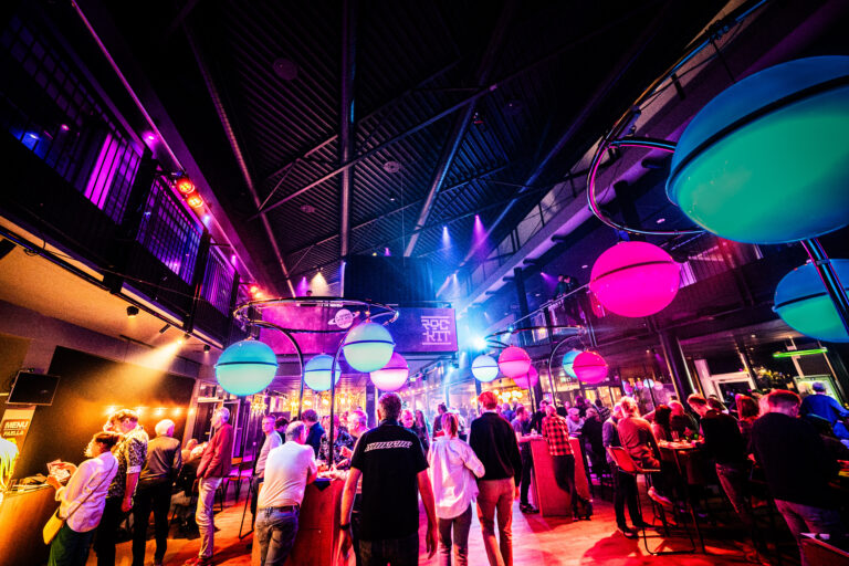 Een levendige nachtclub met feestende mensen en kleurrijke verlichting.