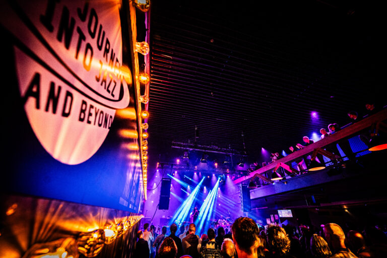 Een druk bezochte muziekshow met kleurrijke lichten en een grote menigte.