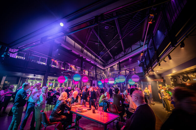 Een drukke uitgaanslocatie met kleurrijke verlichting en vrolijke bezoekers die genieten van de sfeer.