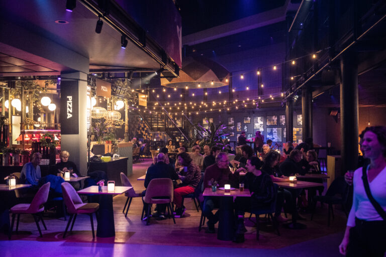 Een drukke bar of restaurant met gezellige verlichting en mensen die genieten van hun tijd.