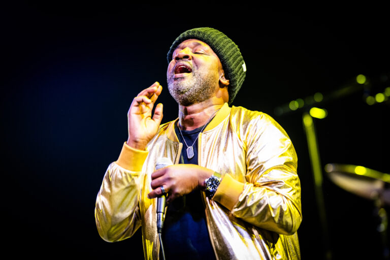 Een muzikant zingt op het podium en lijkt emotioneel betrokken bij het optreden.