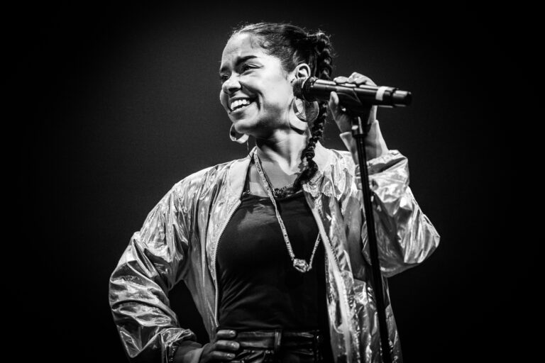 Een zangeres die met een microfoon in de hand op het podium staat en glimlacht.