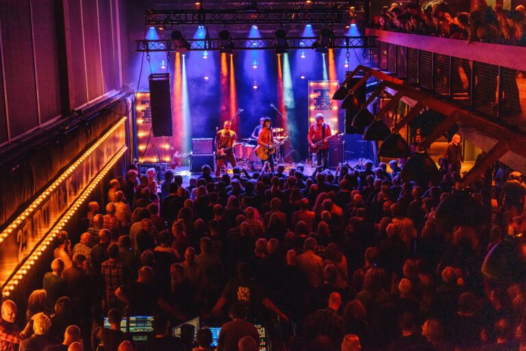 Een live band speelt voor een volle zaal met kleurrijke verlichting.