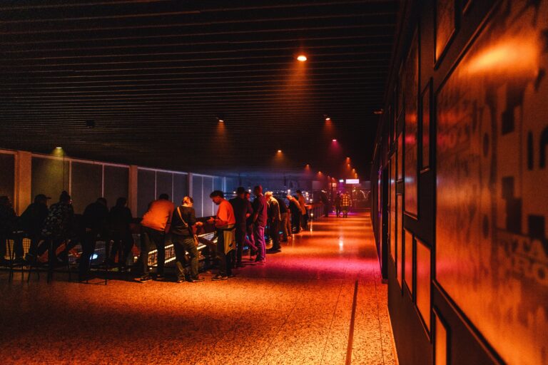 Een lange gang met mensen die bezig zijn met apparatuur, verlicht door sfeervolle oranje en blauwe lichten.