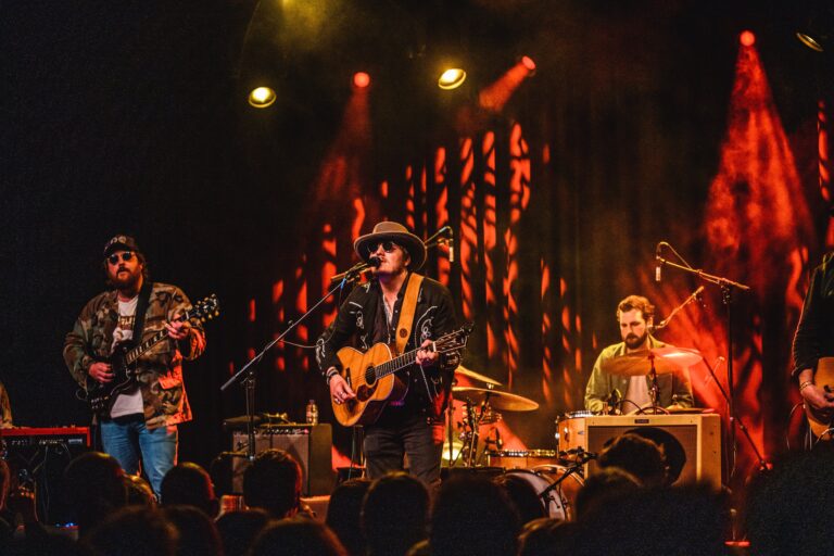 Een band speelt live op het podium met kleurrijke verlichting.