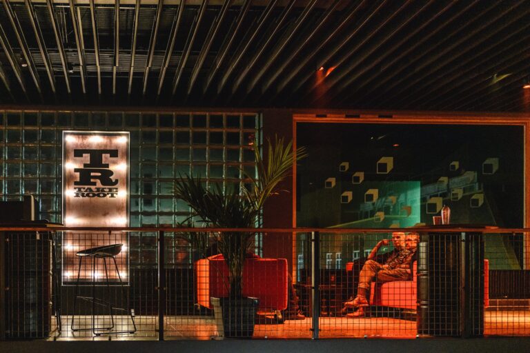 Een sfeervol ingericht café met een opvallende neonverlichting en comfortabele zitplaatsen.