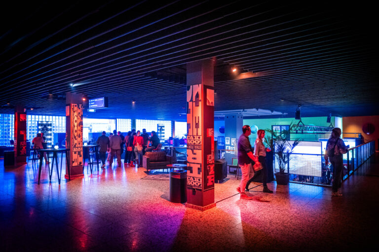 Een moderne bar met kleurrijke verlichting en mensen die interactie hebben.