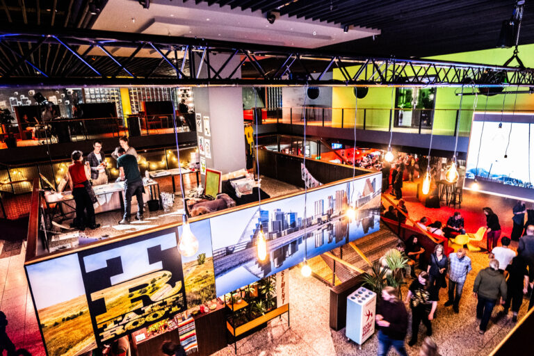 Een overzicht van een modern café of restaurant met verschillende zithoeken en een levendige sfeer.