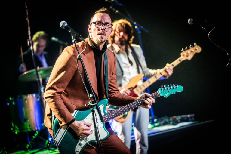 Een muzikant speelt gitaar op het podium tijdens een live optreden.
