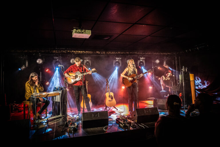 Een band geeft een live optreden op een podium met kleurrijke verlichting.
