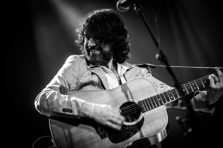 Een muzikant speelt gitaar op het podium in een sfeervolle setting.
