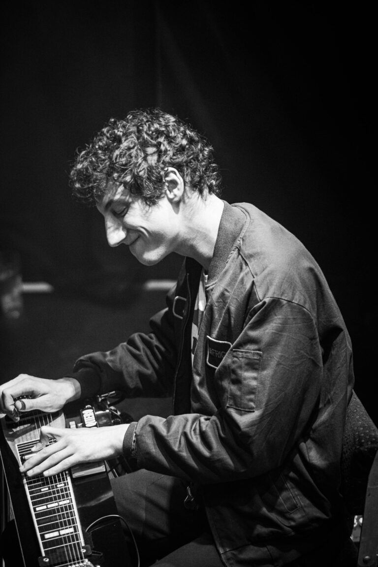 Een muzikant die gefocust op een instrument aan het spelen is in een donkere omgeving.