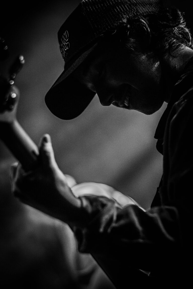 Een silhouet van een muzikant die een gitaar speelt, verlicht door een zachte lichtstraal.