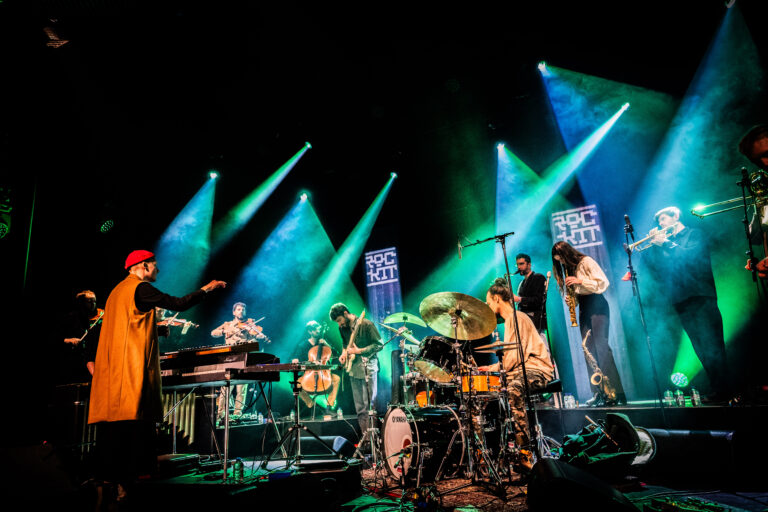 Een liveband speelt op een podium met kleurrijke verlichting.