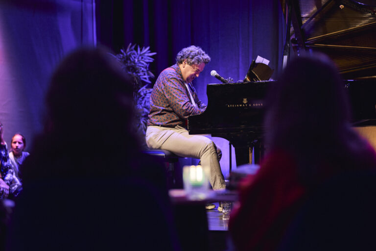 Man die piano speelt op een vleugel.