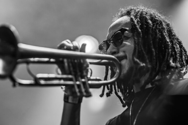 Een muzikant speelt op een trompet terwijl hij naar voren leunt.