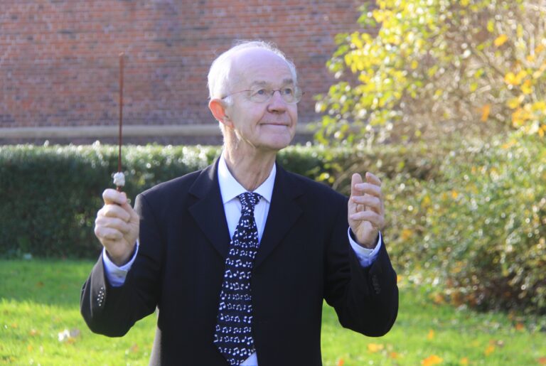 Gerard Wiarda met zijn dirigenten stok in zijn hand.