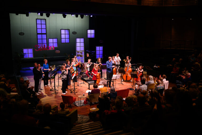 Vrolijk gekleed muziek ensemble op een podium.