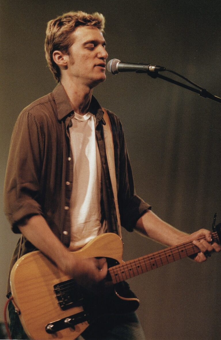 Man die aan het zingen is en zichzelf begeleid met een gitaar