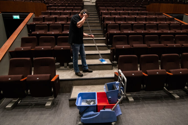 Schoonmaker in Grote Zaal De Oosterpoort, aan het dweilen.