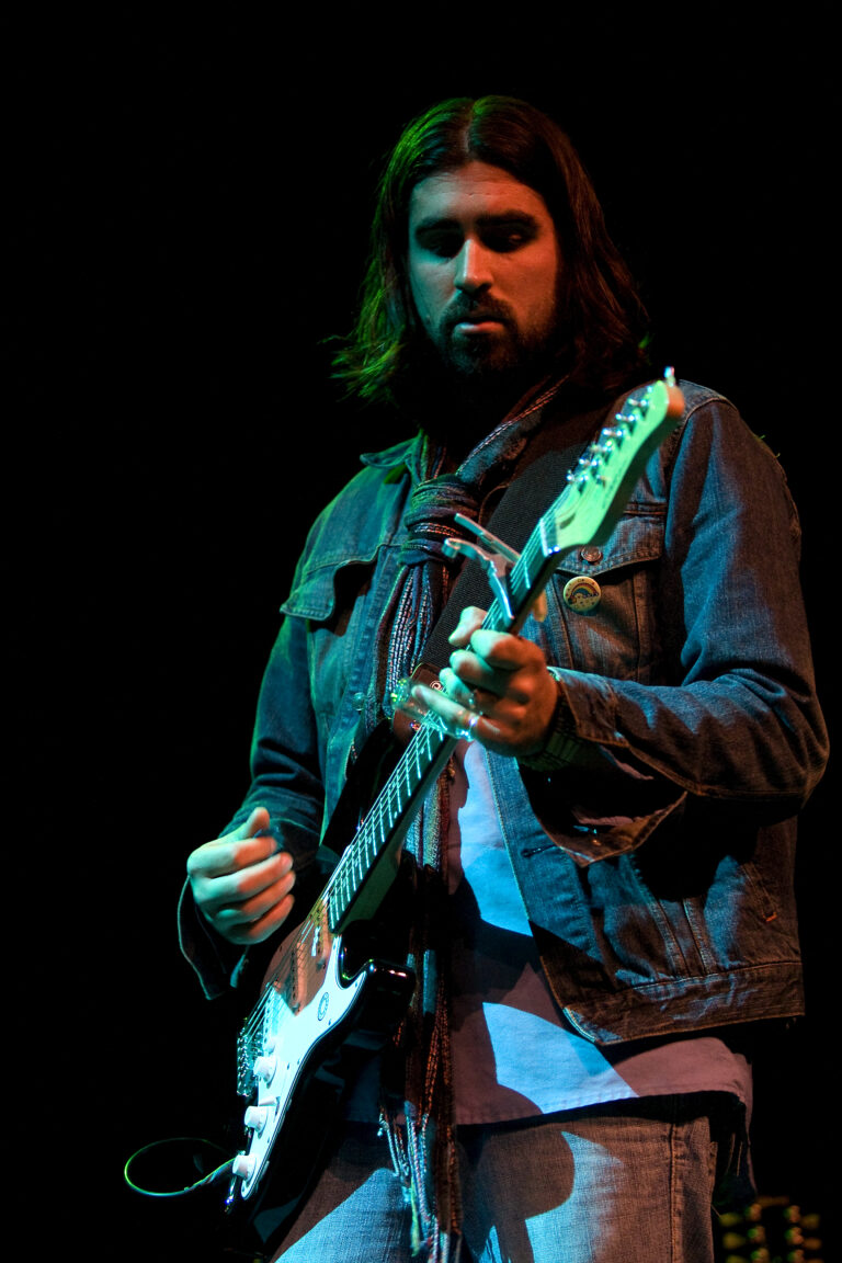 Een muzikant speelt gitaar tijdens een optreden op het podium.
