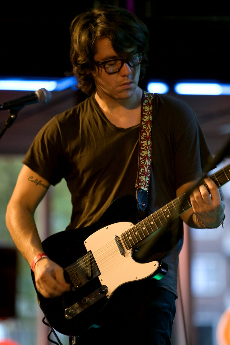 Een muzikant speelt op een elektrische gitaar tijdens een optreden.