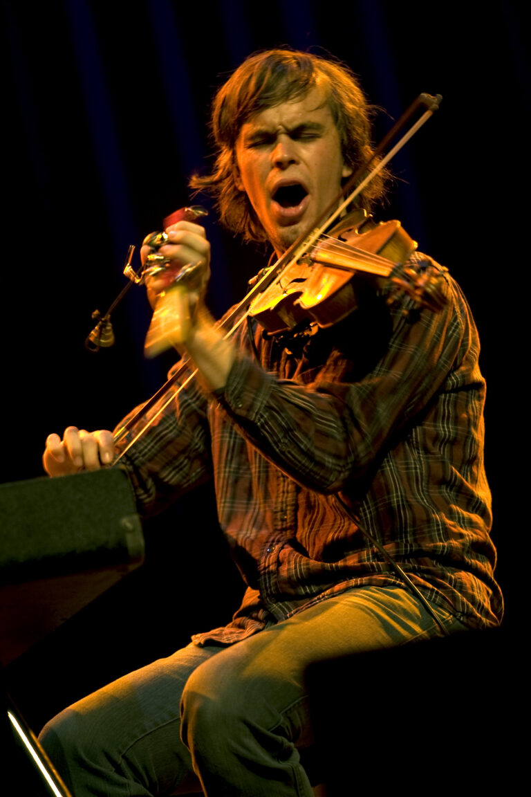Een muzikant speelt enthousiast viool op het podium.