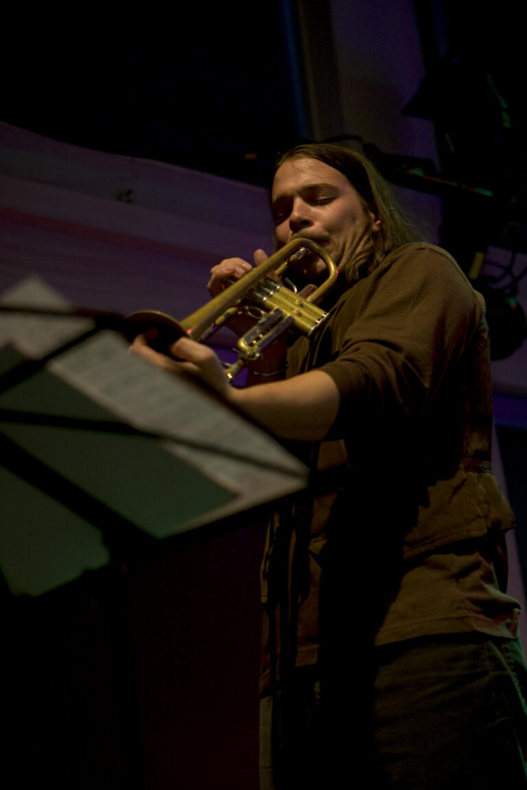 Een muzikant speelt op een trompet terwijl hij zich richt op een muziekstandaard.