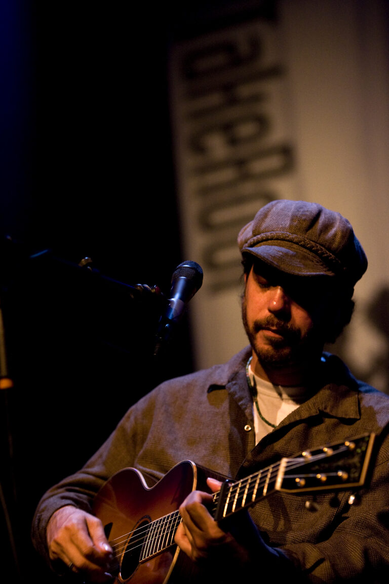 Een muzikant speelt op een gitaar tijdens een optreden op het podium.